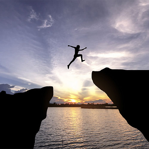 Man jumping from one cliff to another