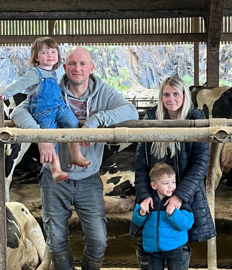 smaXtec testimonial Robin White stands with his wife and children in front of his Holstein cows