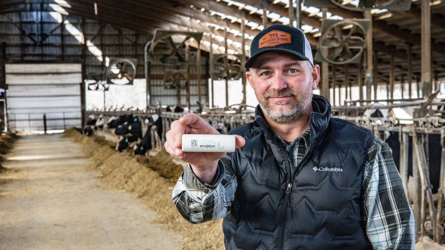 smaXtec testimonial Nathan Brearley shows a bolus to the camera while standing in his barn